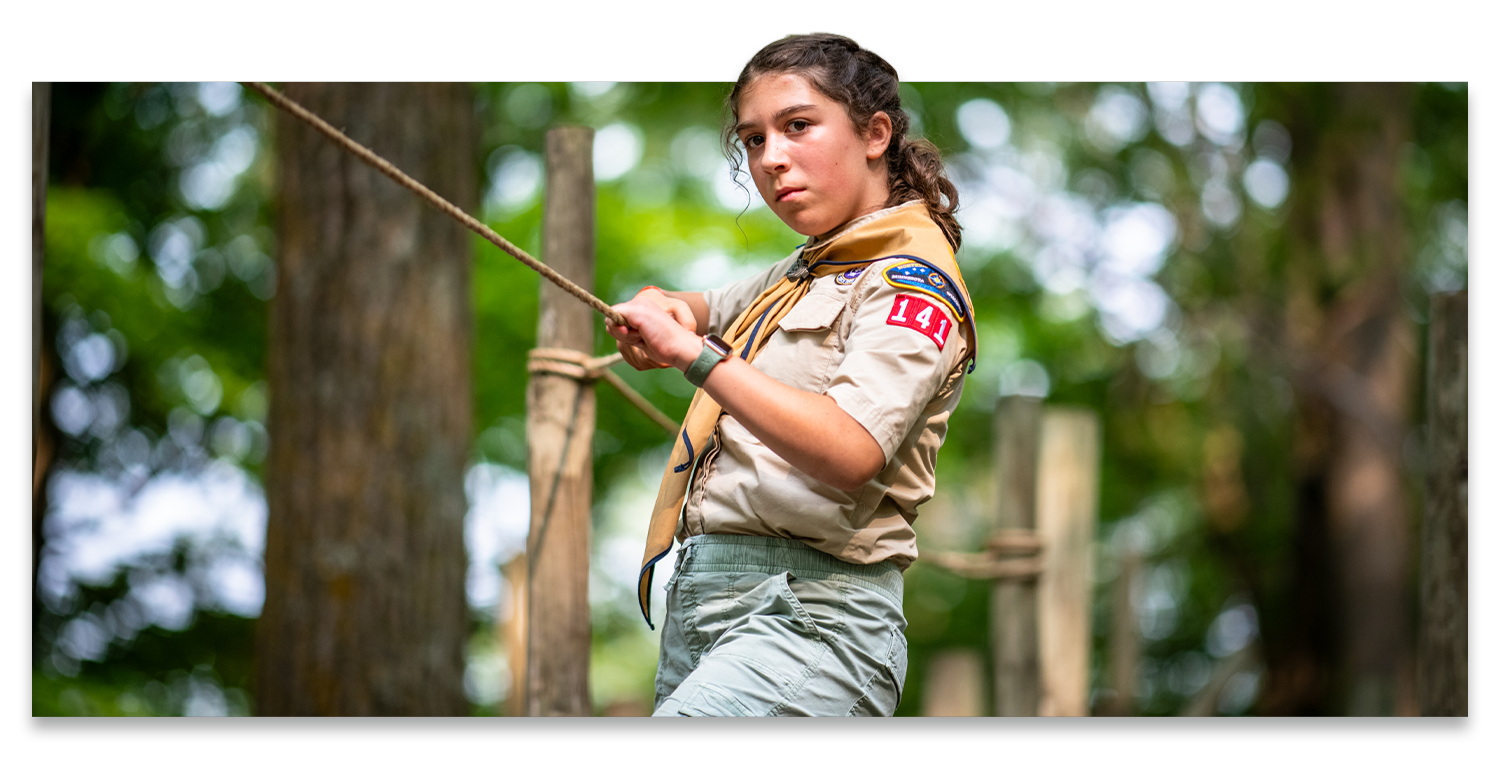 A teenage girl with a serious expression navigates a lashed obstacle course