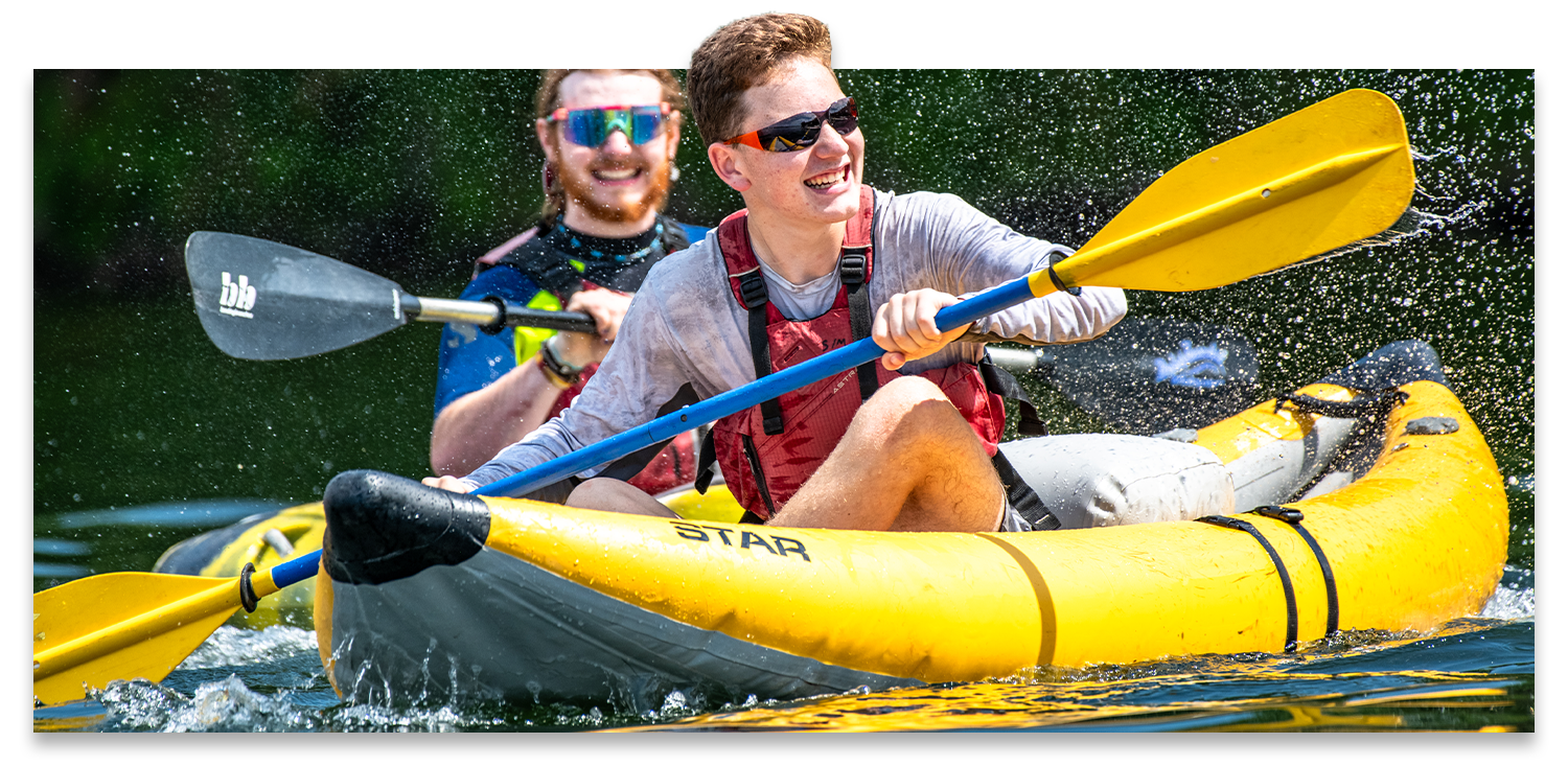 Two teenagers are laughing while kayaking